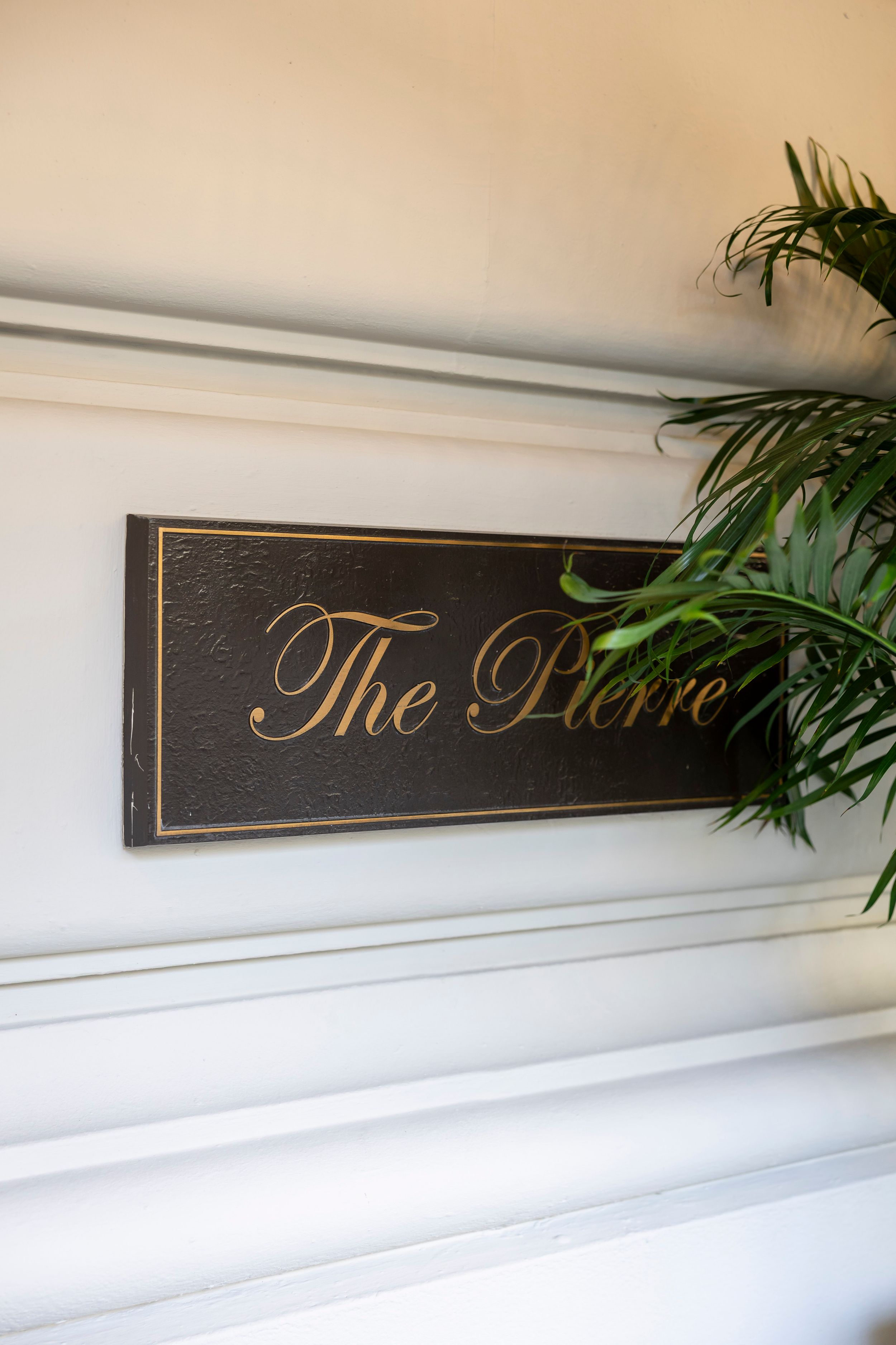 Elegant wall signage reading 'The Pierre' in gold script lettering.