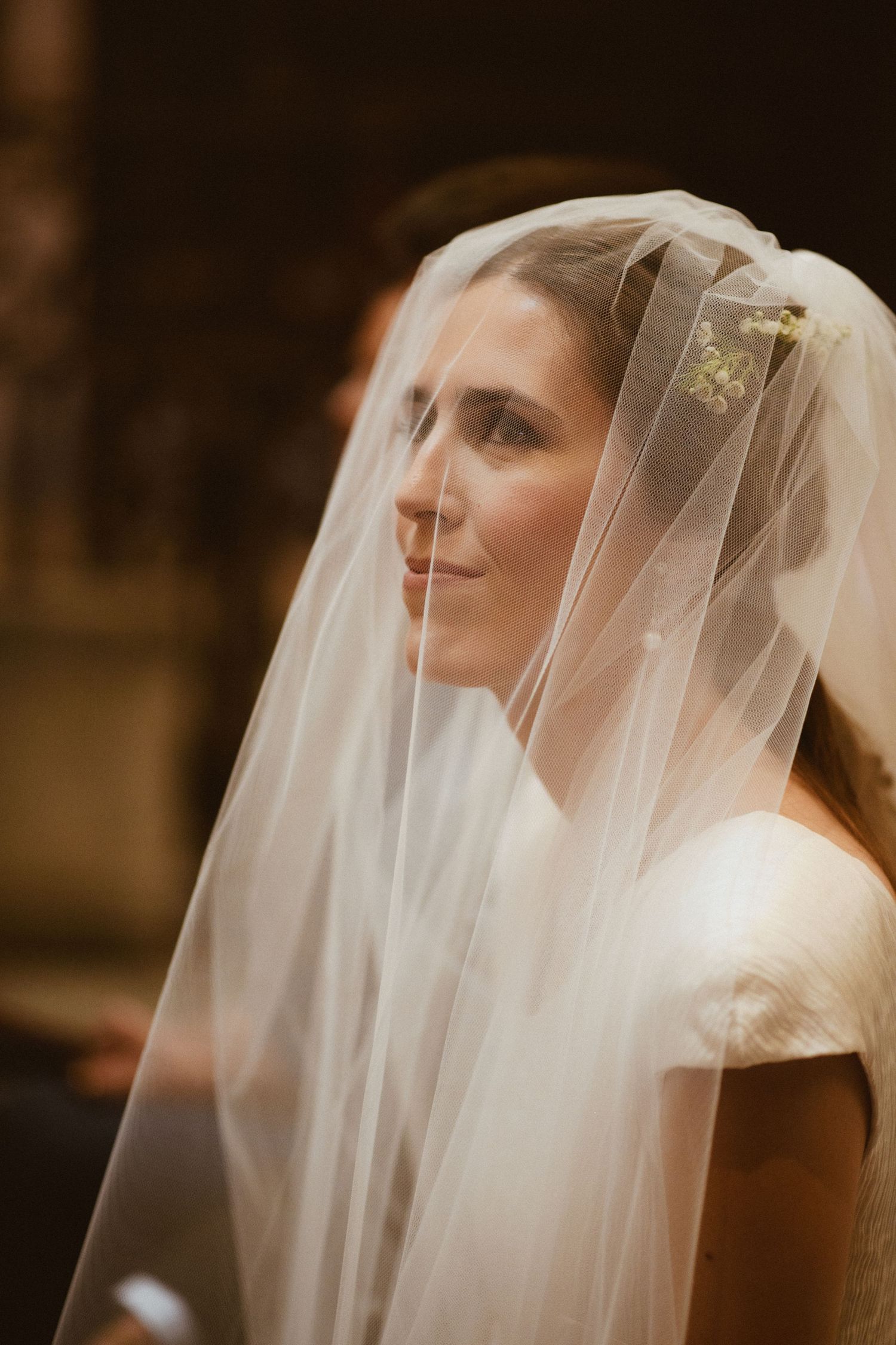 A bride wearing a delicate white veil is captured in a series of soft-lit profile portraits at her wedding.