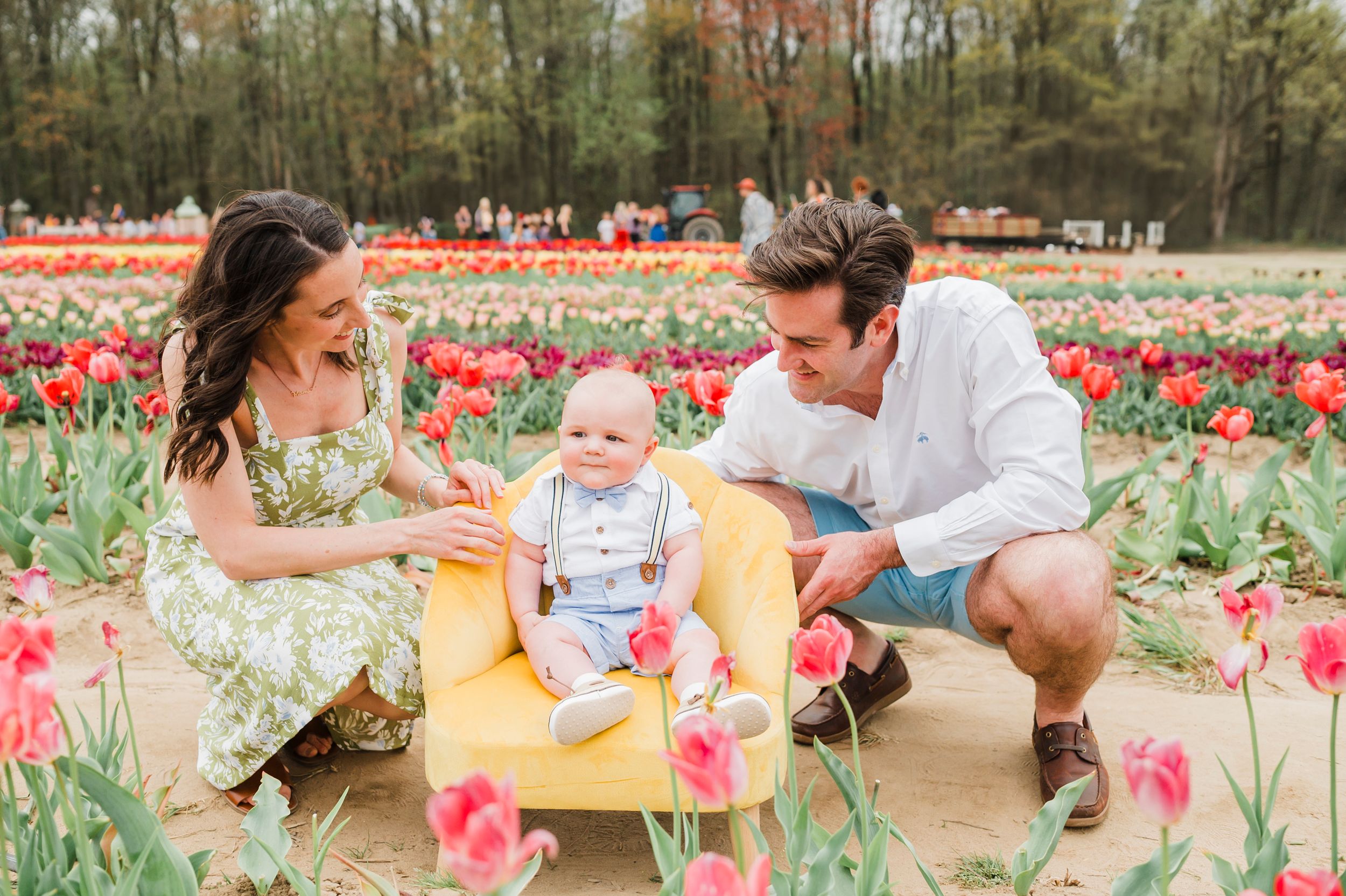 People sitting among vibrant pink tulips in a field during a spring photo shoot.
