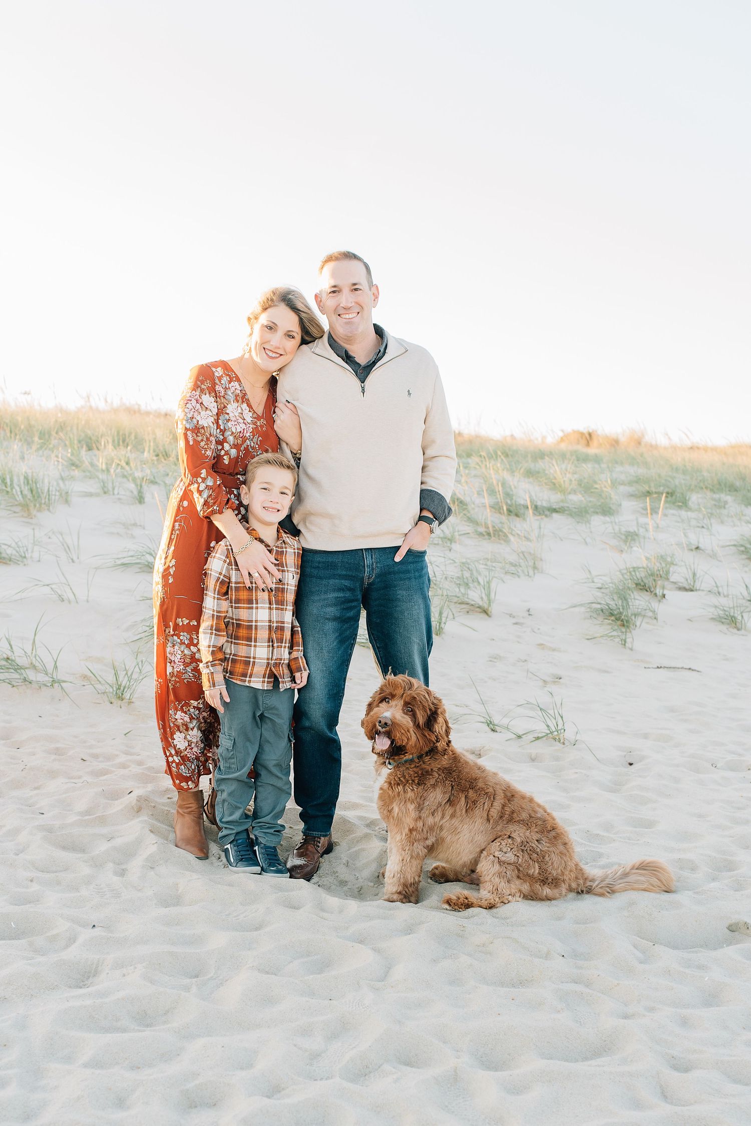 A family of four poses on the beach for a fall photo session with Lauren Marie photography.