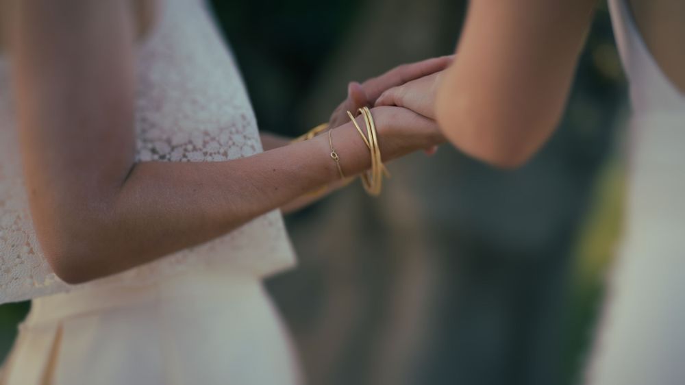 Close-up view of hands exchanging wedding rings during a ceremony with a blurred natural background.