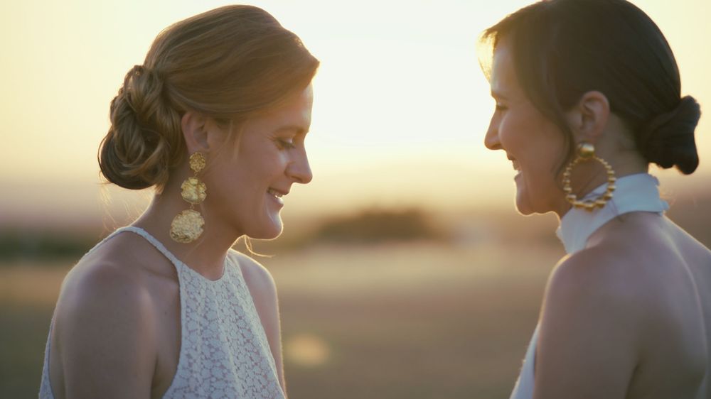Two people sharing an intimate moment at sunset while standing close together by the ocean.