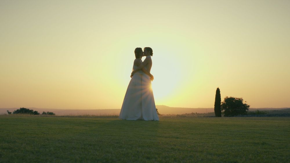 A scenic silhouette of wheat fields at sunset with figures standing on a hill against a golden sky.