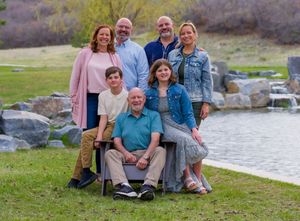 Group gathered outdoors by a lake on green grass enjoying a casual autumn day together.
