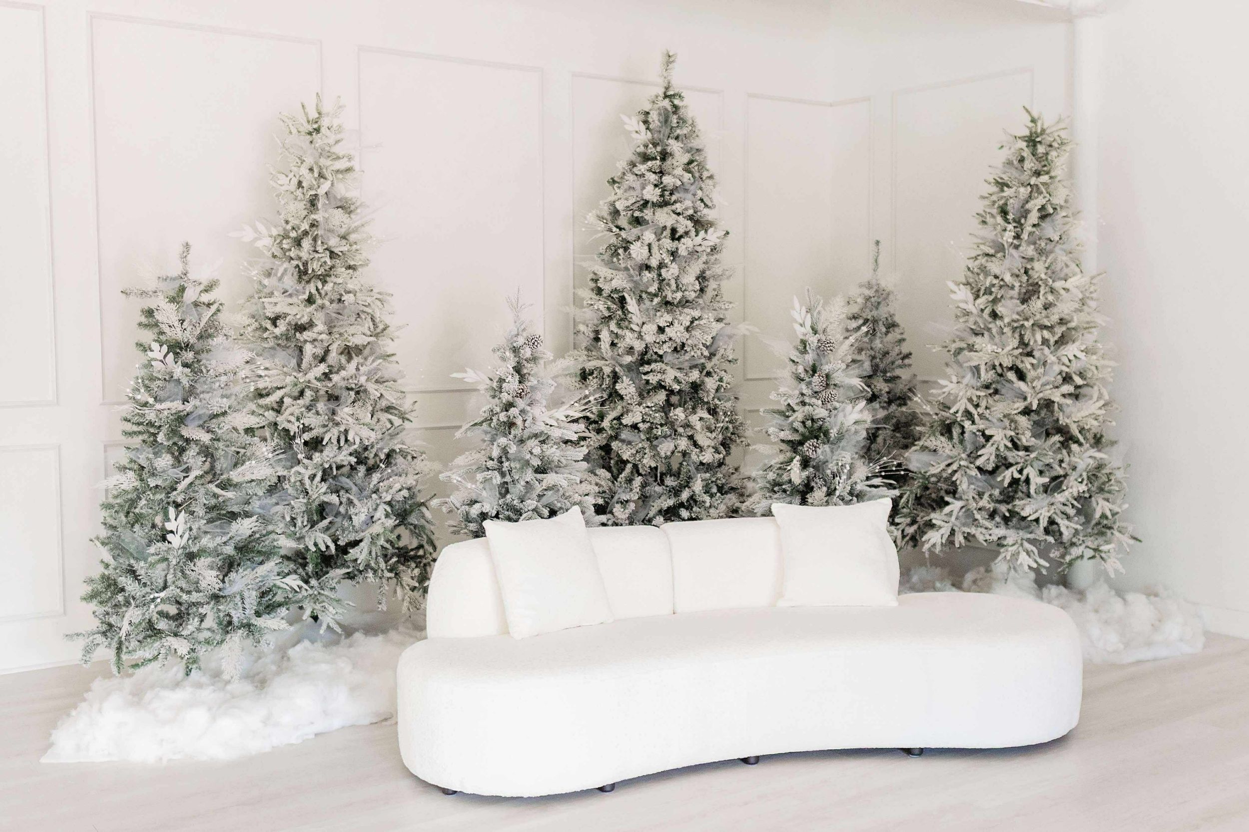 A minimalist winter scene with frosted evergreen trees and a curved white bench against a light gray backdrop.