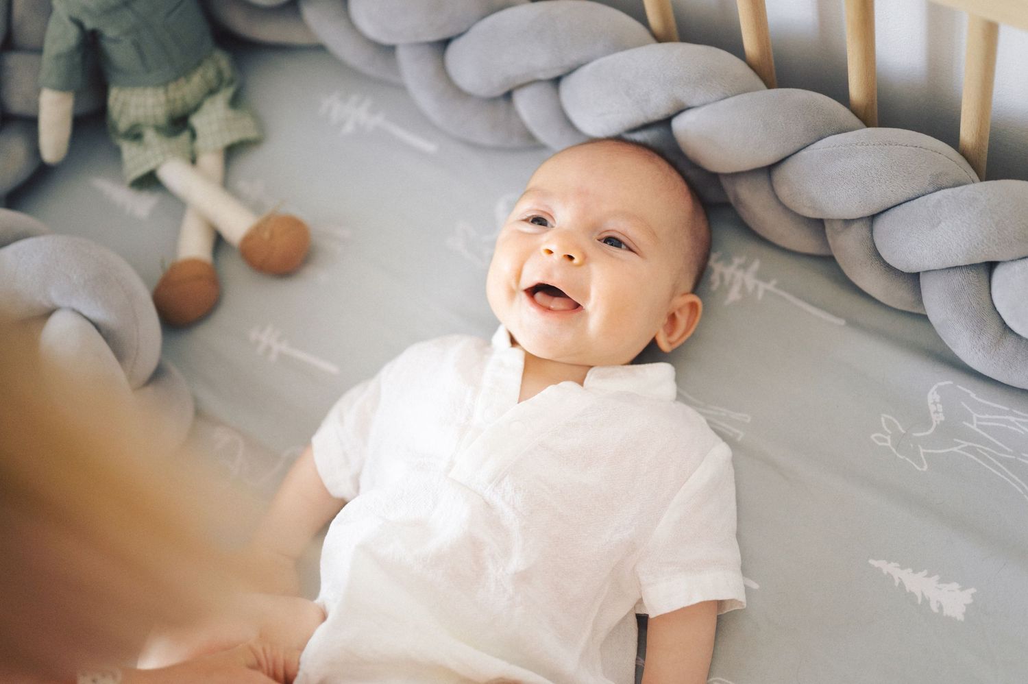 A series of connected photos showing a baby in white clothing laying on a light gray surface and smiling playfully.