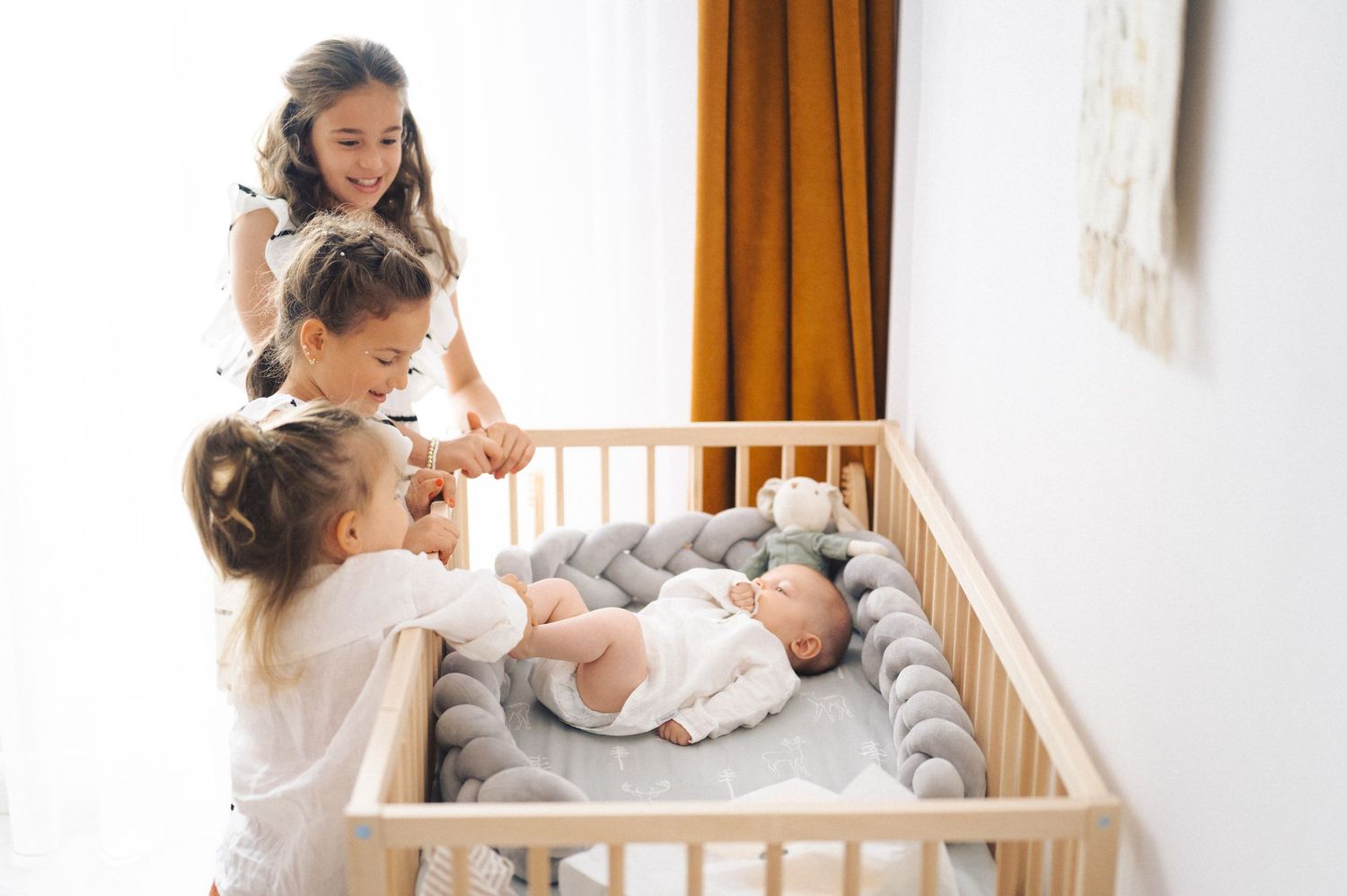 A mother and child share tender moments together in a warmly lit nursery setting by a wooden crib.