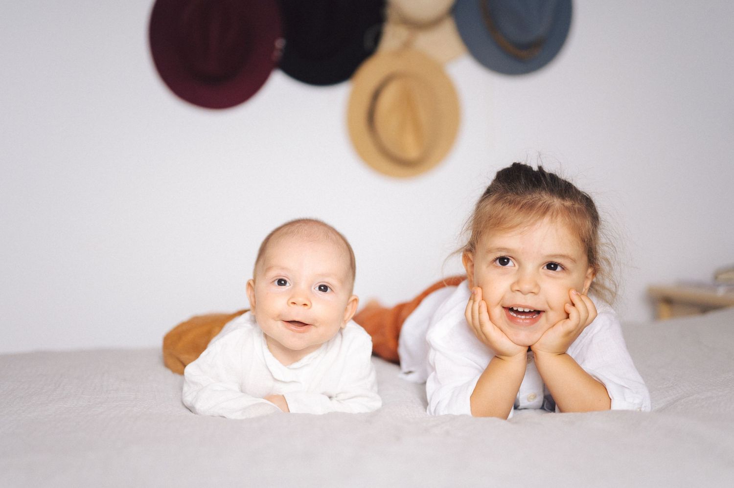 Seven connected headshots show baby and toddler portraits lying on white backgrounds in similar poses.