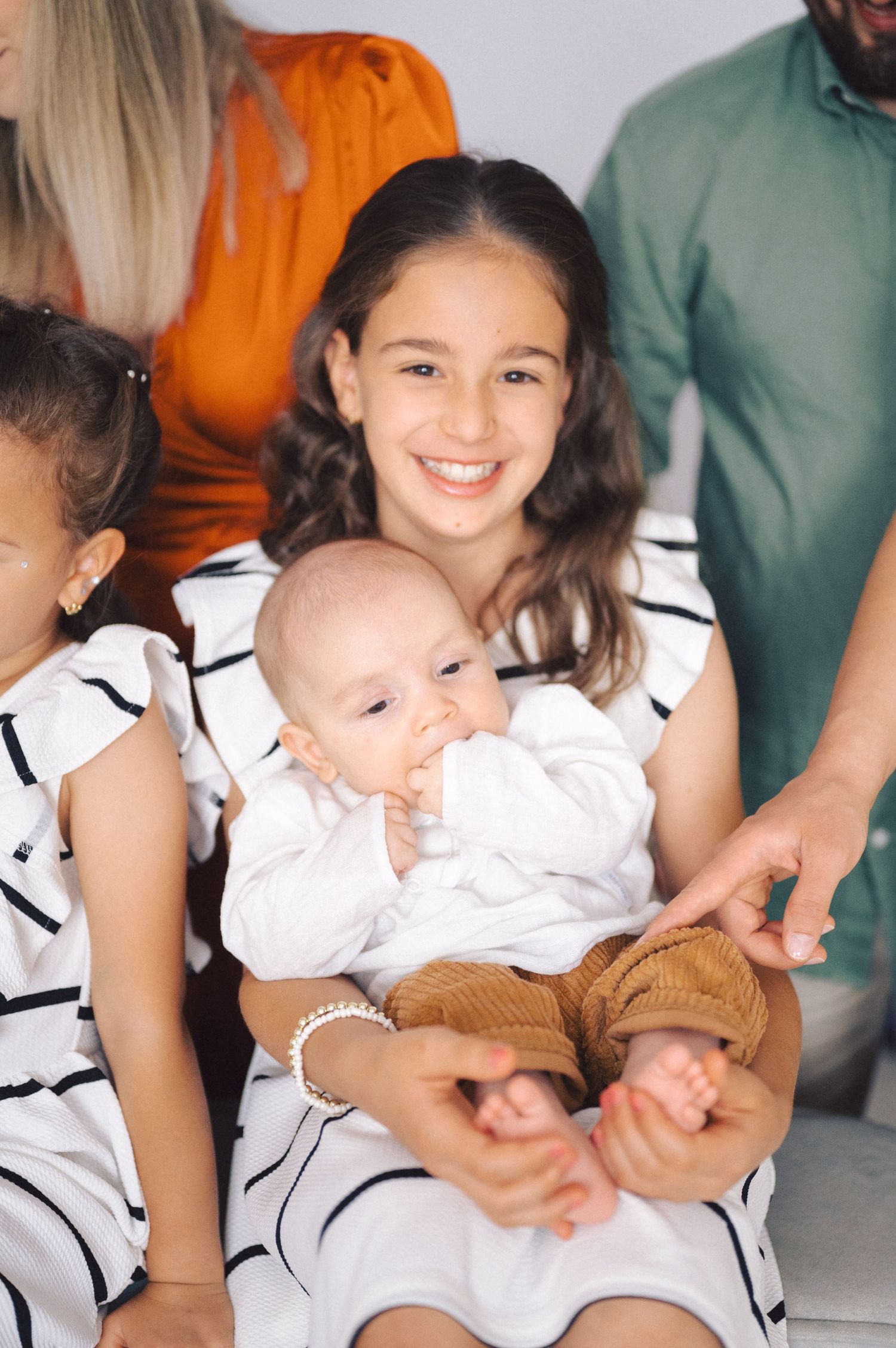 A series of five photos showing a baby in white clothing being held and playing with a brown teddy bear.