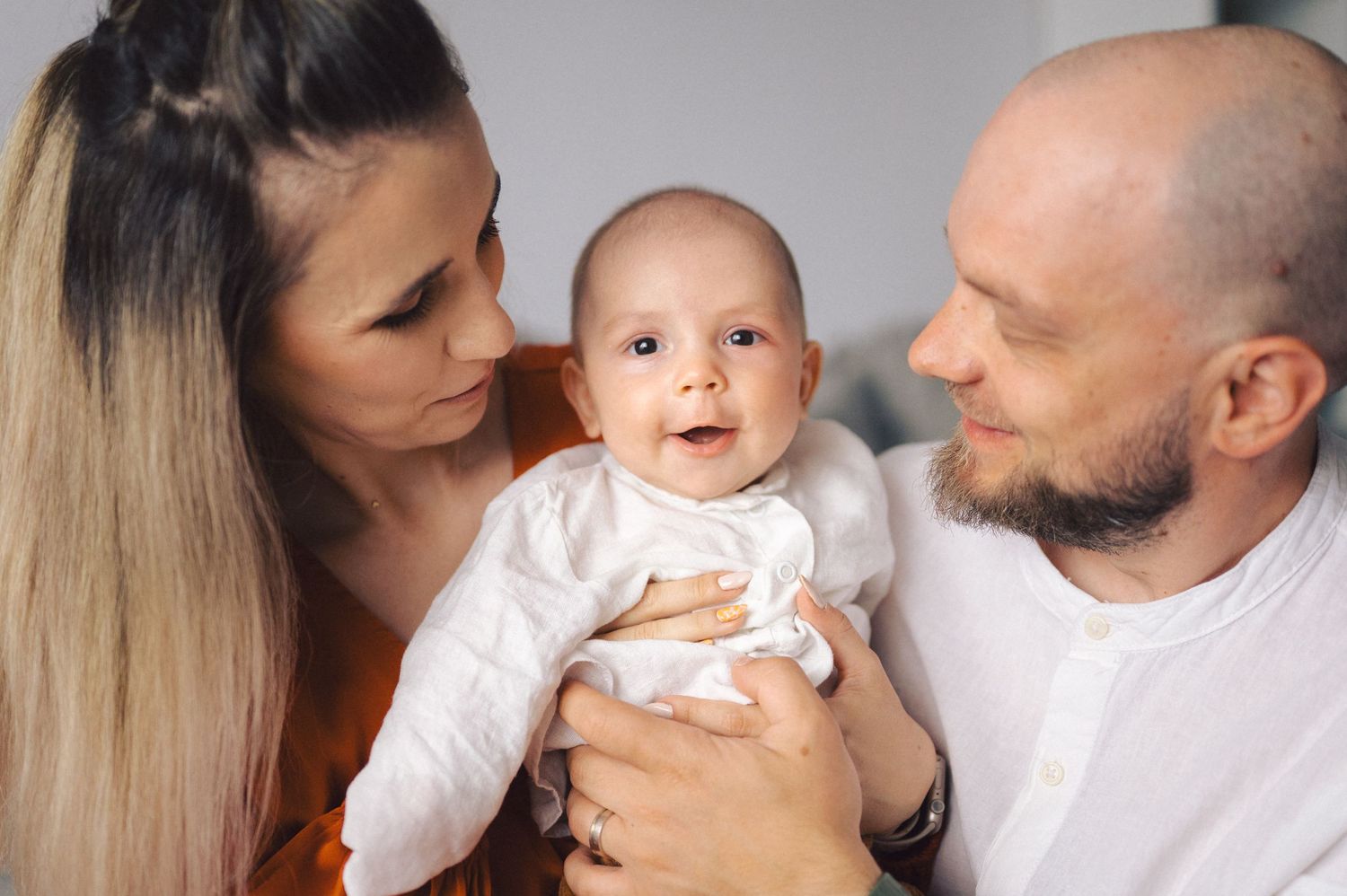 A loving family shares tender moments and kisses with their baby in a series of connected photos.