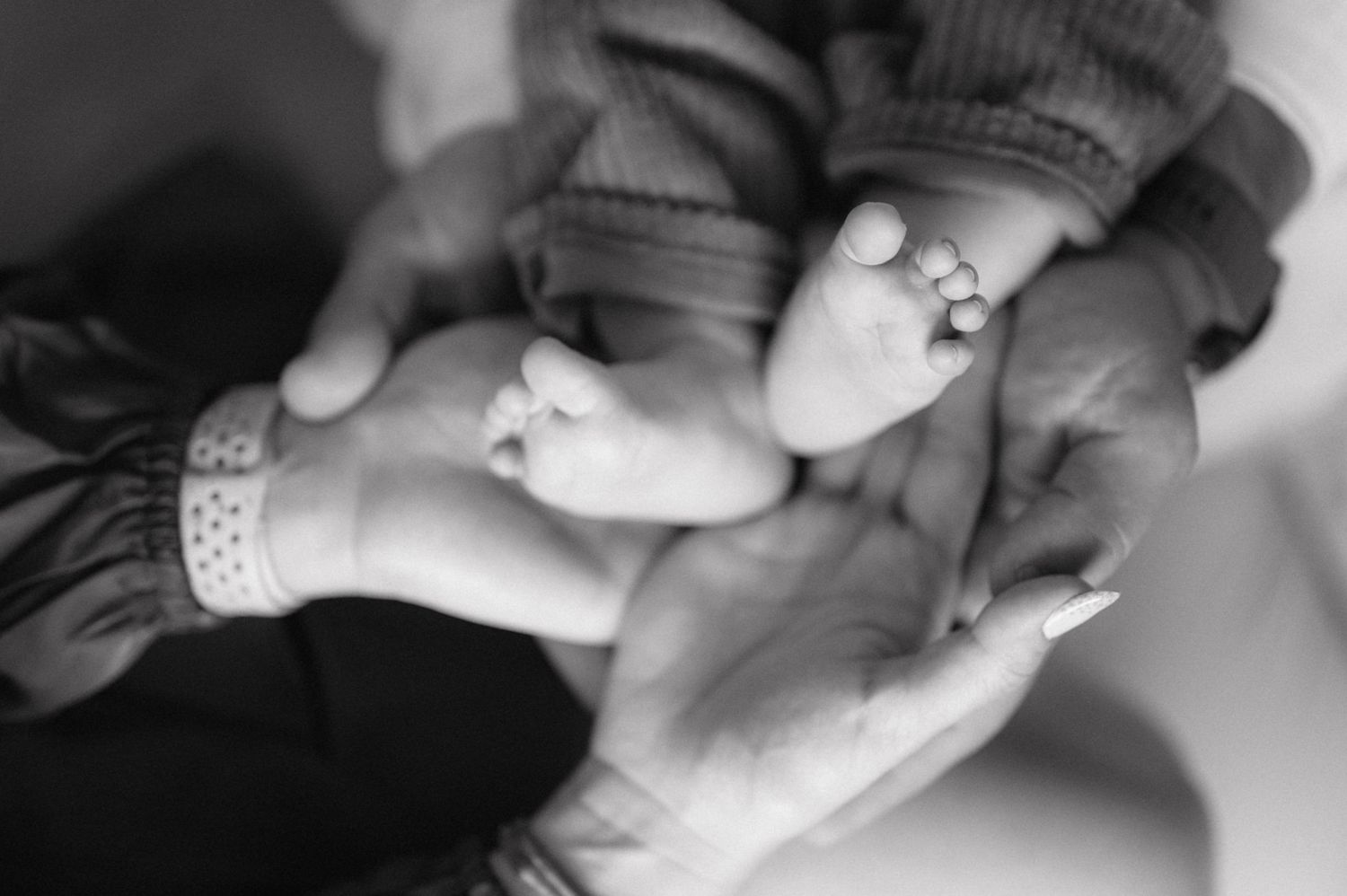 Closeup black and white series of newborn baby fingers intertwined with adult hands showing tender family moments.