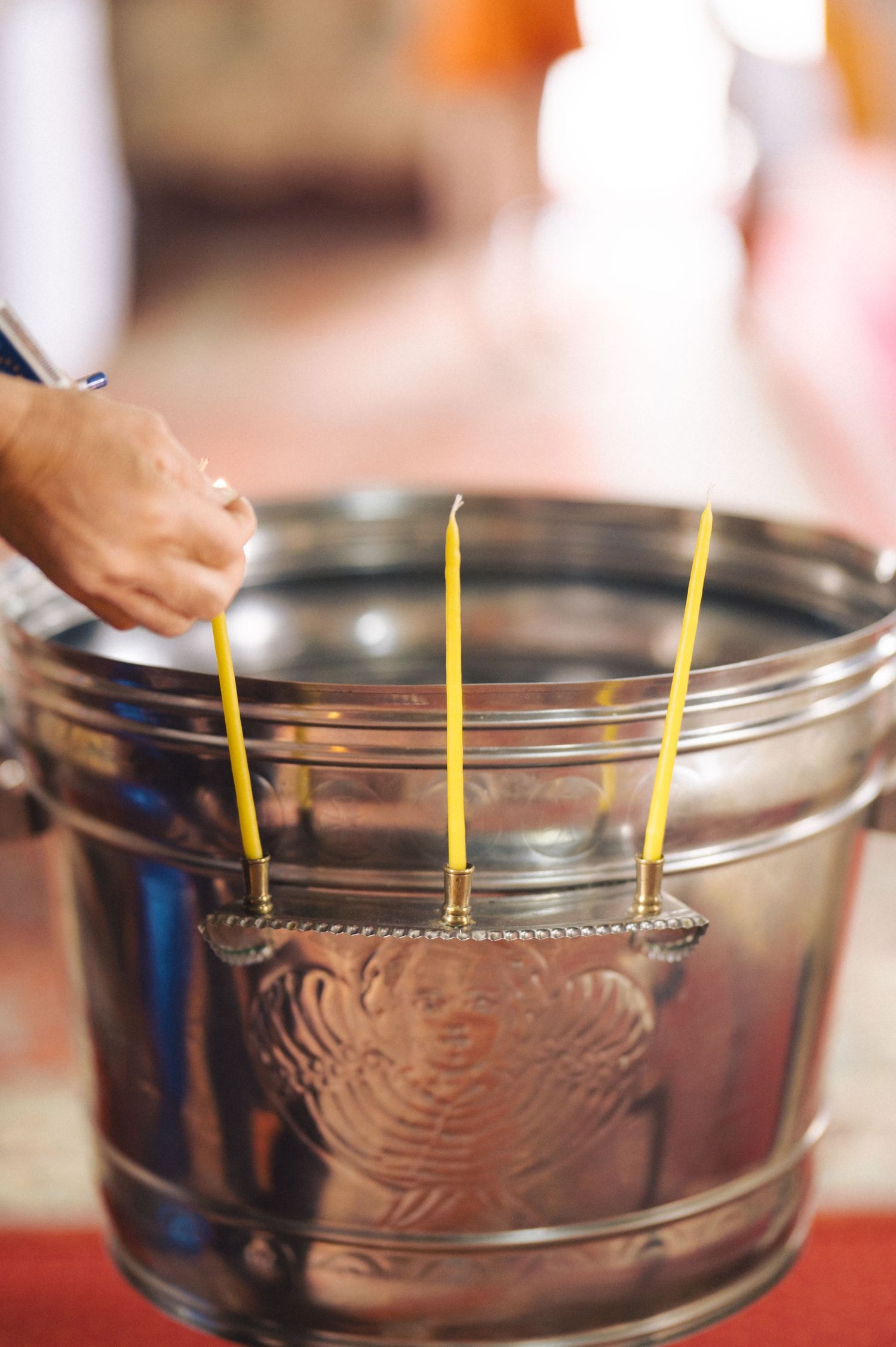 Three thin yellow candles are placed evenly spaced in a round glass Starbucks coffee measuring cup.