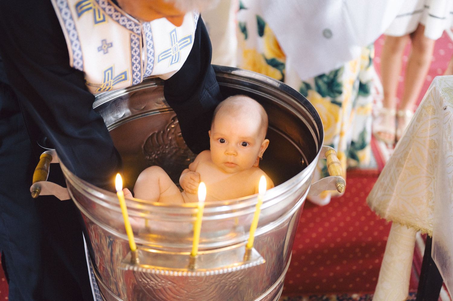 A baby doll sits in a vintage brown glass jar with lit birthday candles arranged around the rim.