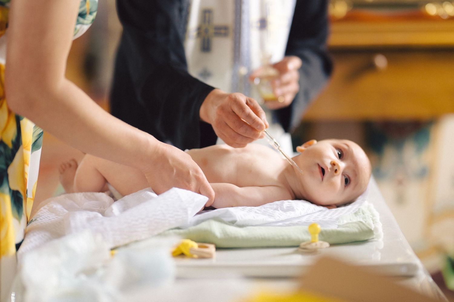 A baby receiving care and attention while lying on a changing table during a special occasion.
