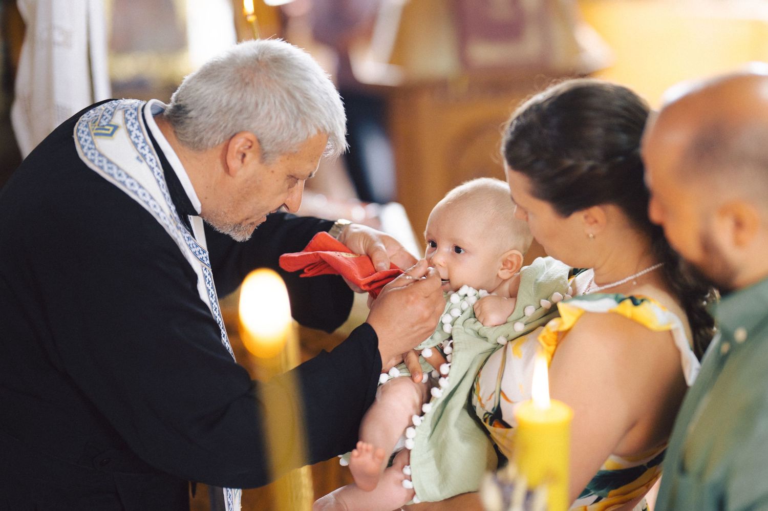 A small child reaching out during Catholic communion service at a church altar with the priest administering the sacrament.