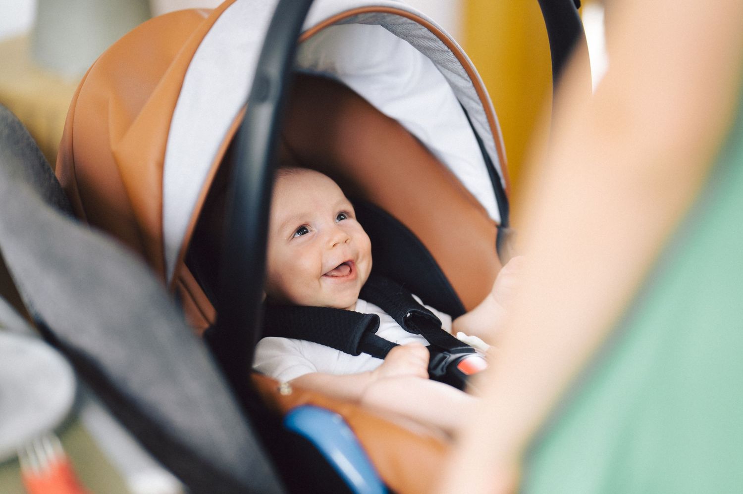A baby strapped securely in an orange and gray stroller looks up with a bright expression.