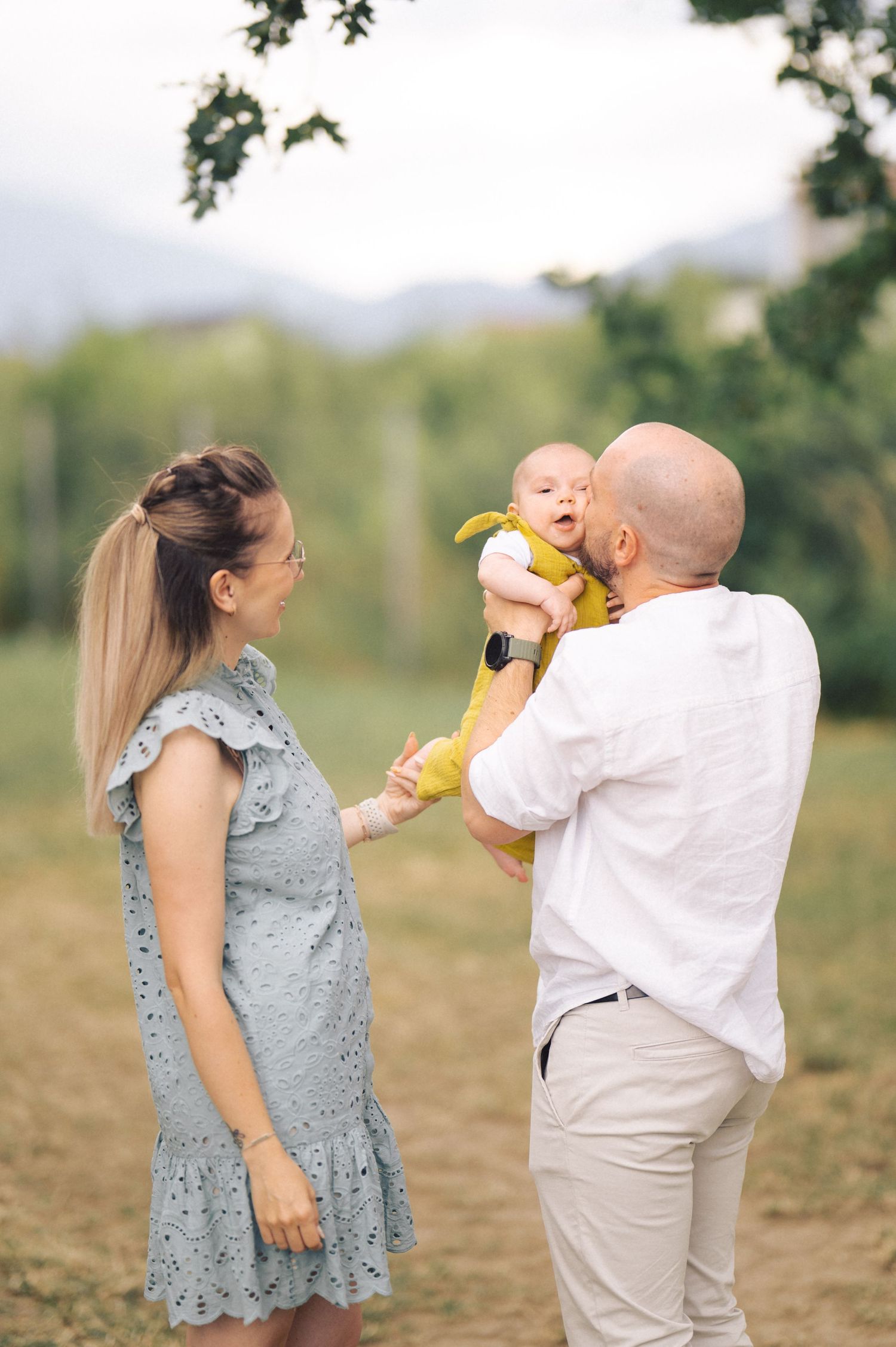 Young family enjoying a tender moment together outdoors in a natural setting on a sunny day.