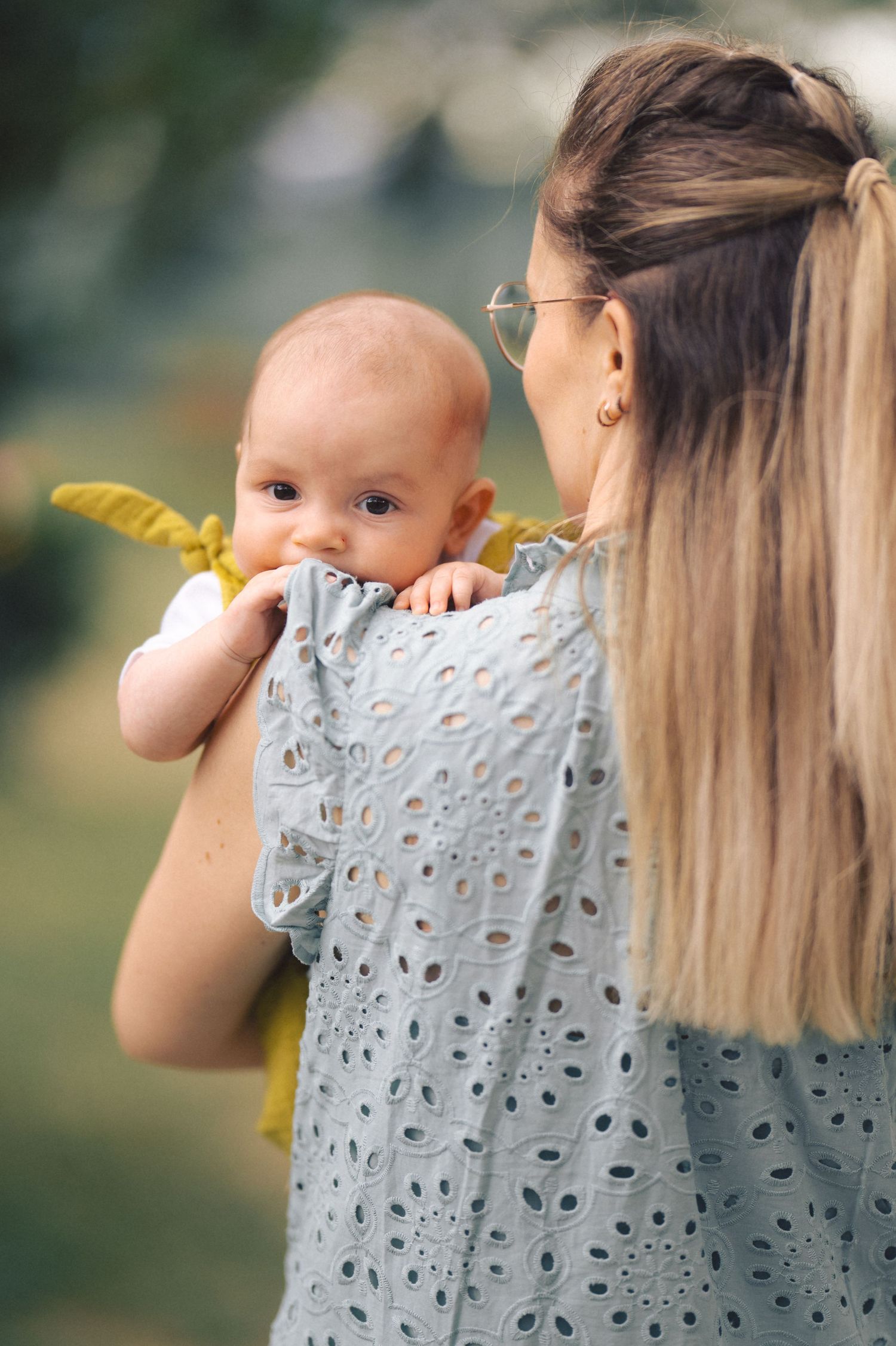 A series of candid photos show a baby being embraced and held by someone in a delicate eyelet pattern top.