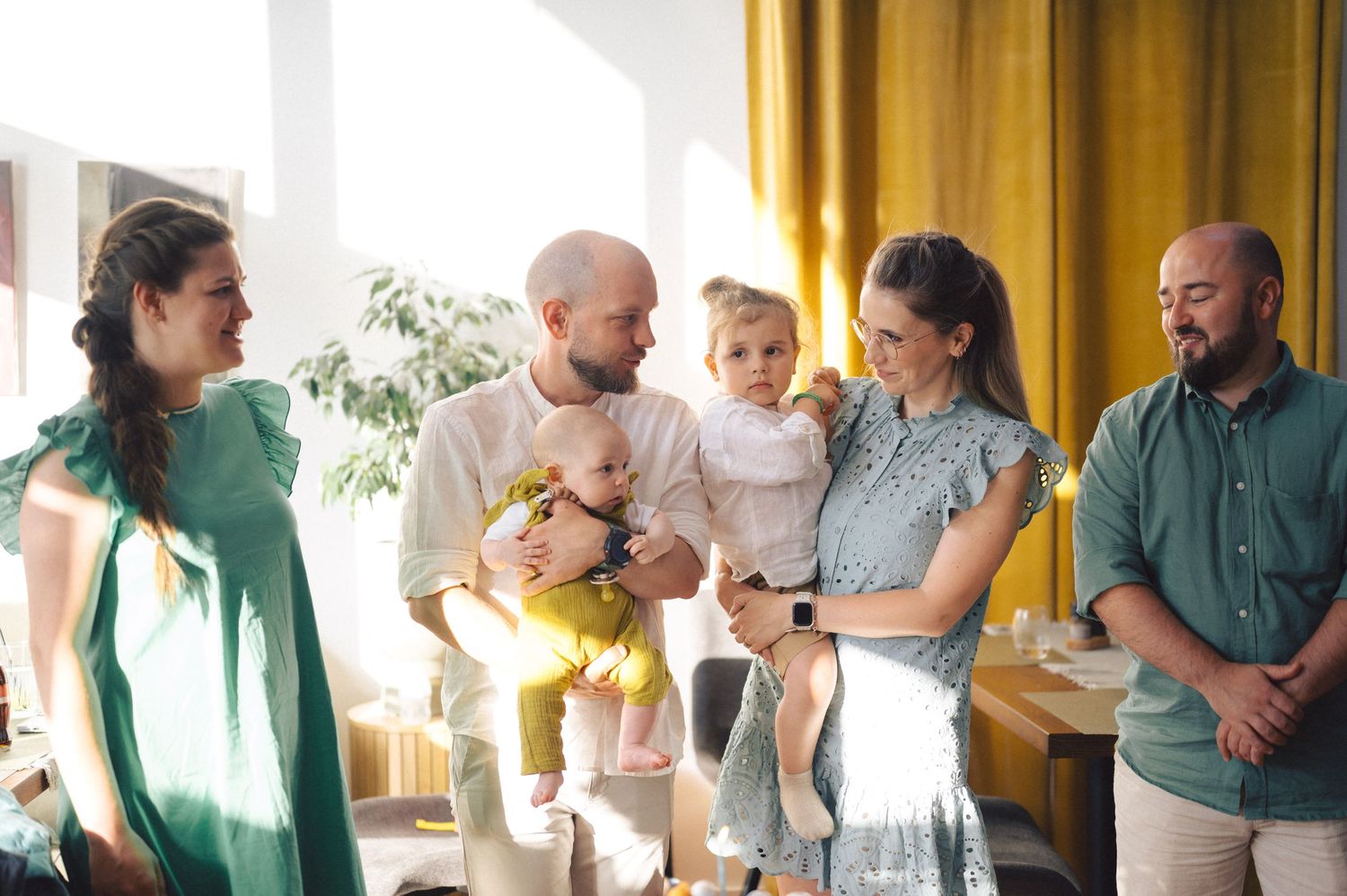 Medical professionals consult and collaborate in a bright hospital hallway with yellow curtains and natural lighting.