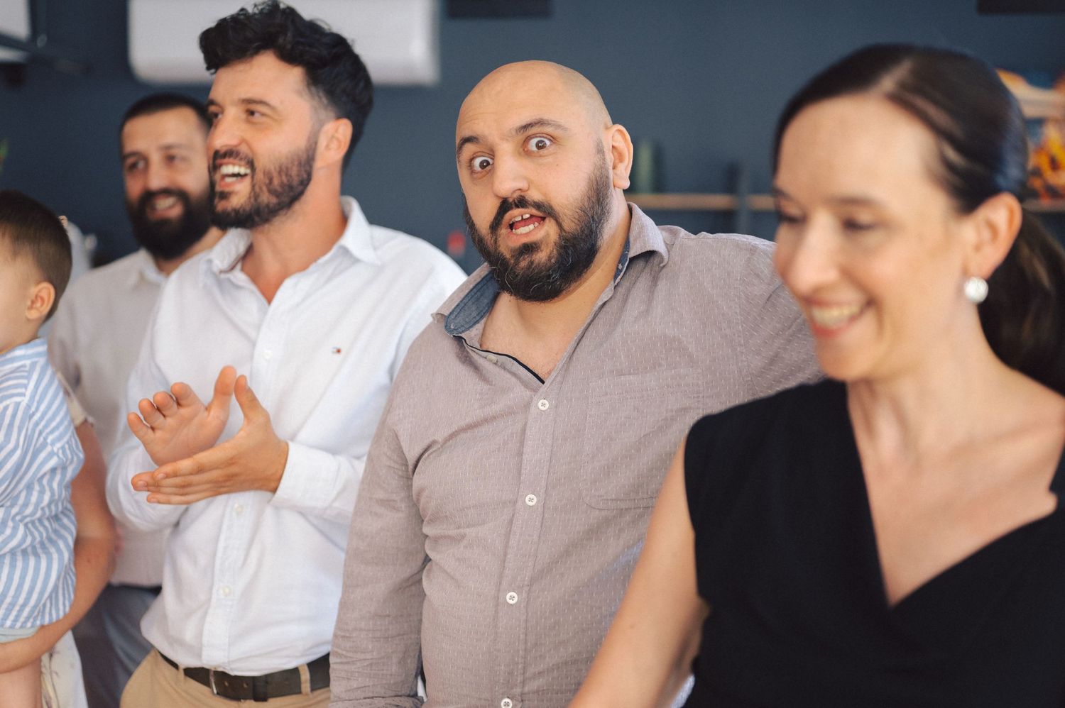 A diverse group of people sit together smiling and engaging during what appears to be a social gathering.