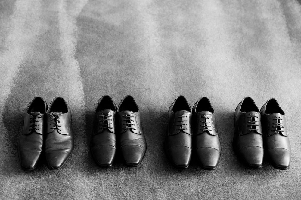 A row of formal black and brown leather dress shoes arranged in a grayscale lineup against a light background.