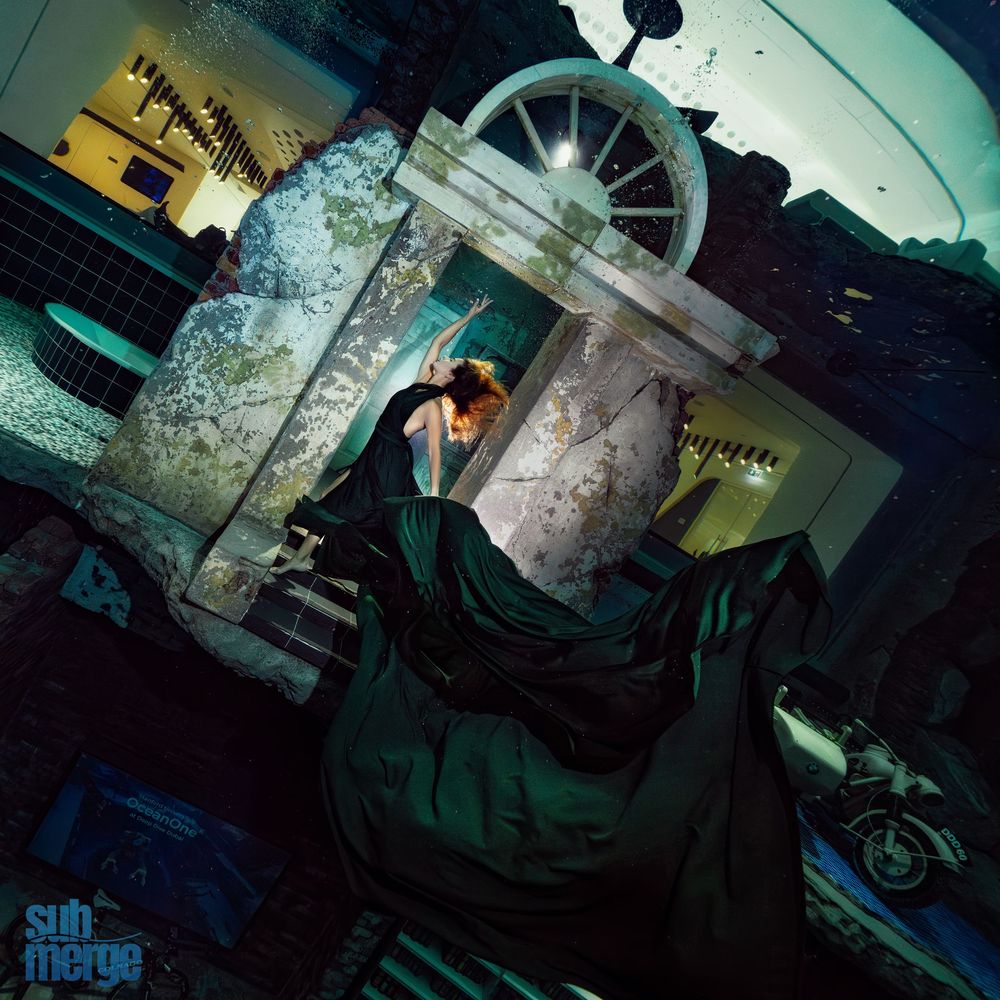 A dark and moody industrial scene with turquoise lighting illuminating machinery and metal fixtures.
