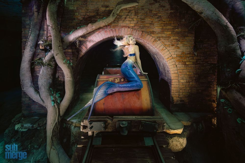 A series of artistic mermaid figures displayed in a mystical underground tunnel with brick archways and dramatic lighting.
