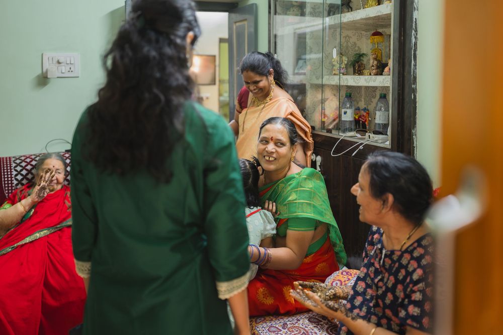 Group gathered in a home interior wearing colorful traditional Indian clothing during a social occasion.