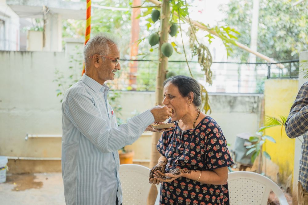 An elderly couple having a conversation in a brightly decorated indoor space with hanging ornaments.