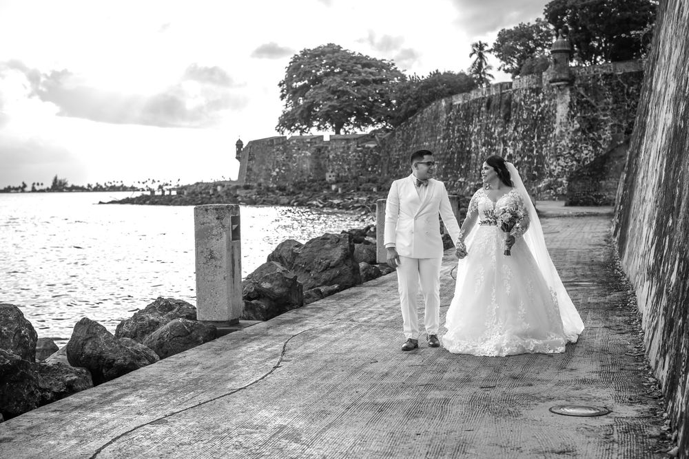 Oceanside wedding ceremony with couples posed against rocky cliffs as waves crash in background.