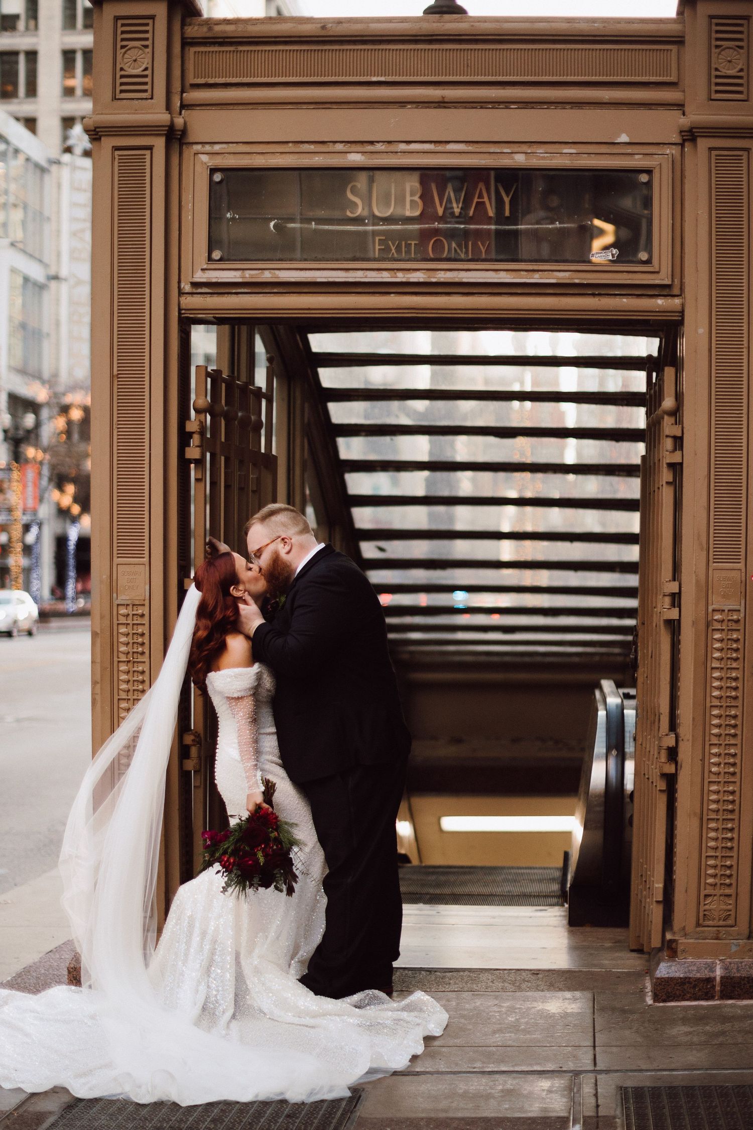 Wedding couple shares romantic moment outside vintage subway entrance.