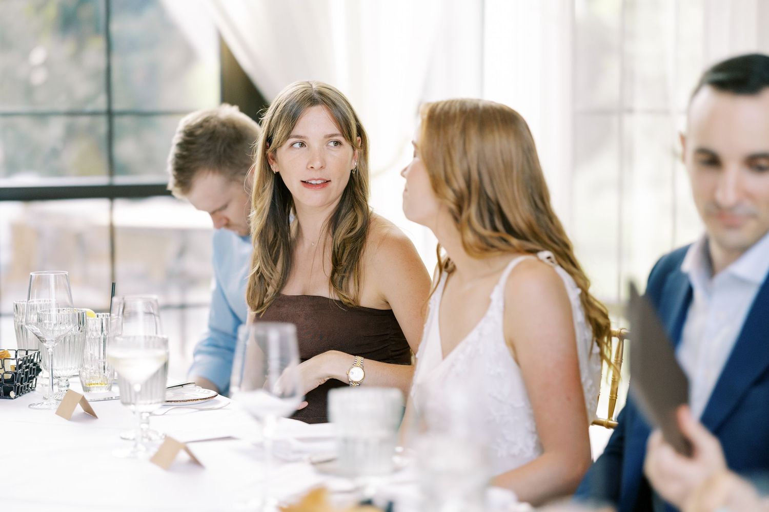 People seated at elegant white dining tables having conversations during a sophisticated social gathering at Ninety Acres and Pendry Natirar