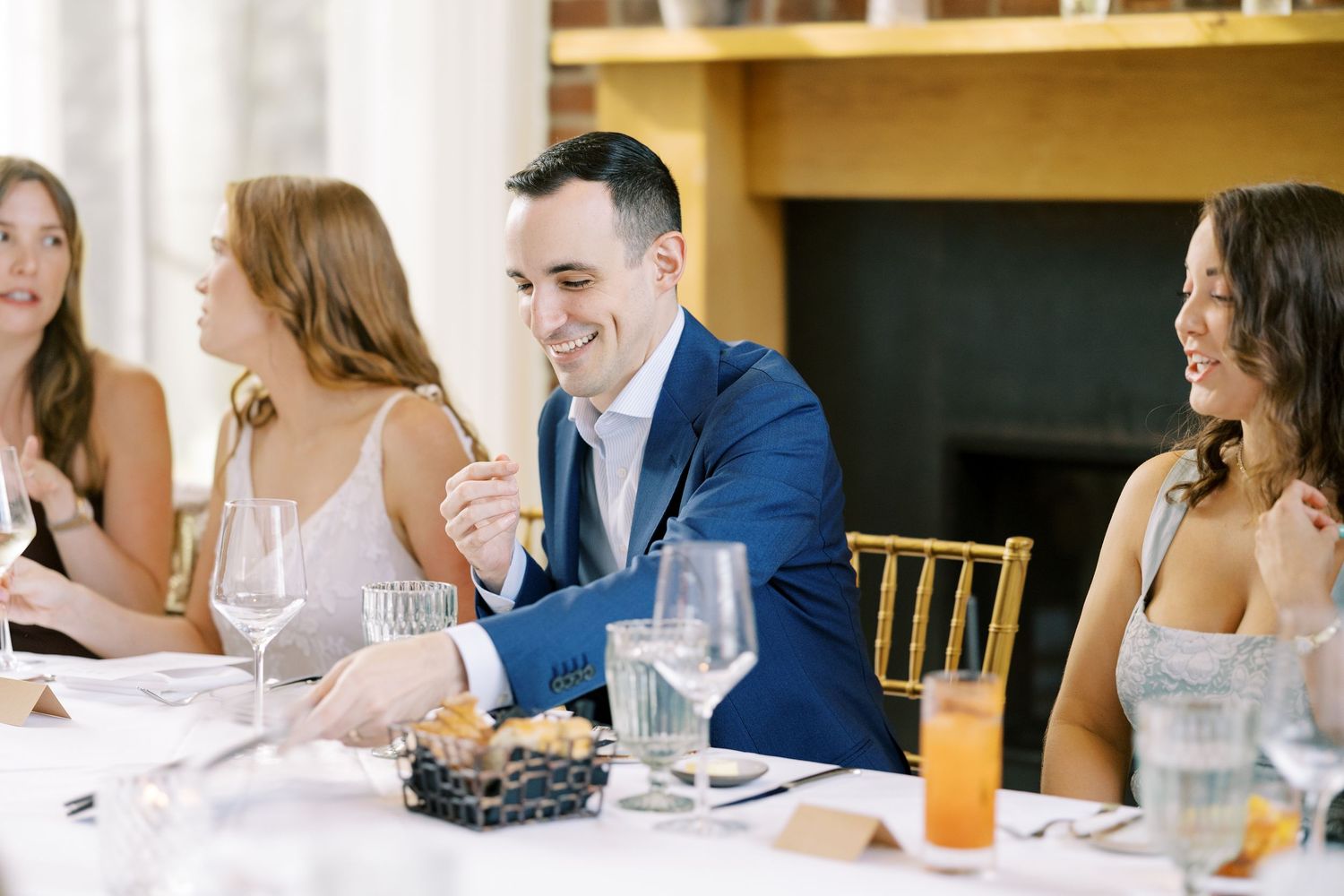 Groom seated at an elegant table engages in conversation during a wedding dinner at Ninety Acres and Pendry Natirar.