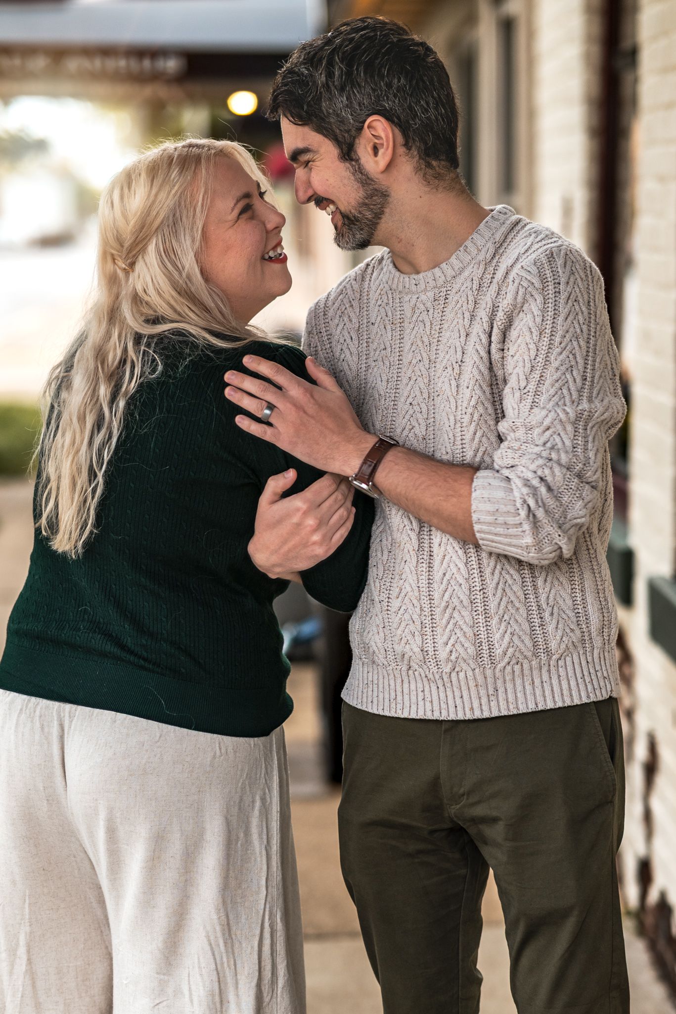 A couple wearing contrasting green and beige sweaters share intimate moments in a series of romantic poses together.