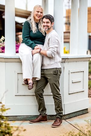 A couple poses playfully together on white porch steps during a romantic outdoor photoshoot.