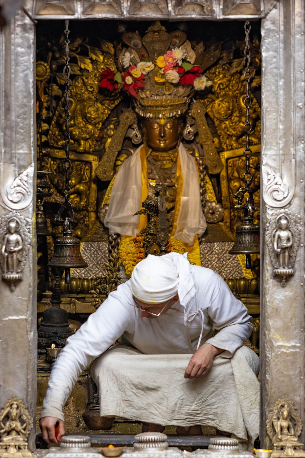 Buddhist temple interior showing ornate golden decorations and statues with figures in white robes.