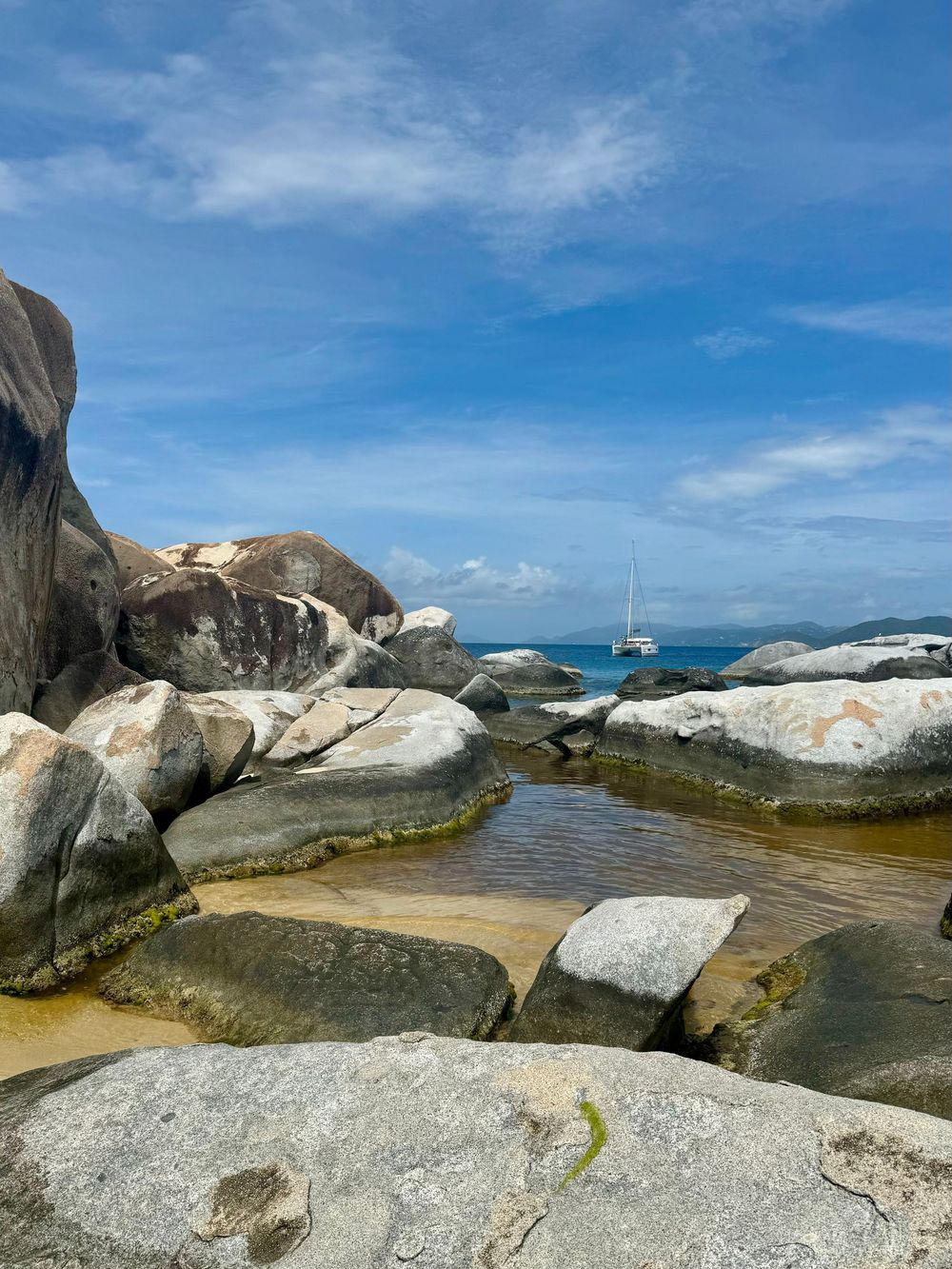Large granite boulders line a pristine beach with turquoise waters and blue skies at The Baths, Virgin Gorda.