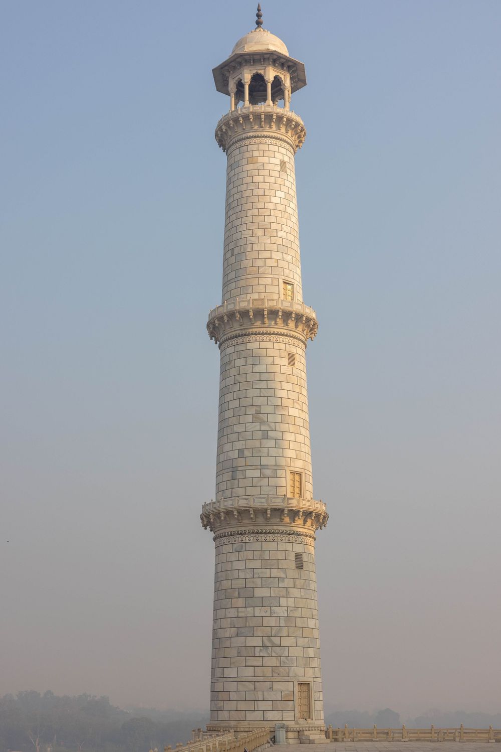 Close-up view of the iconic marble minaret of the Taj Mahal showing intricate architectural details in Agra, India.