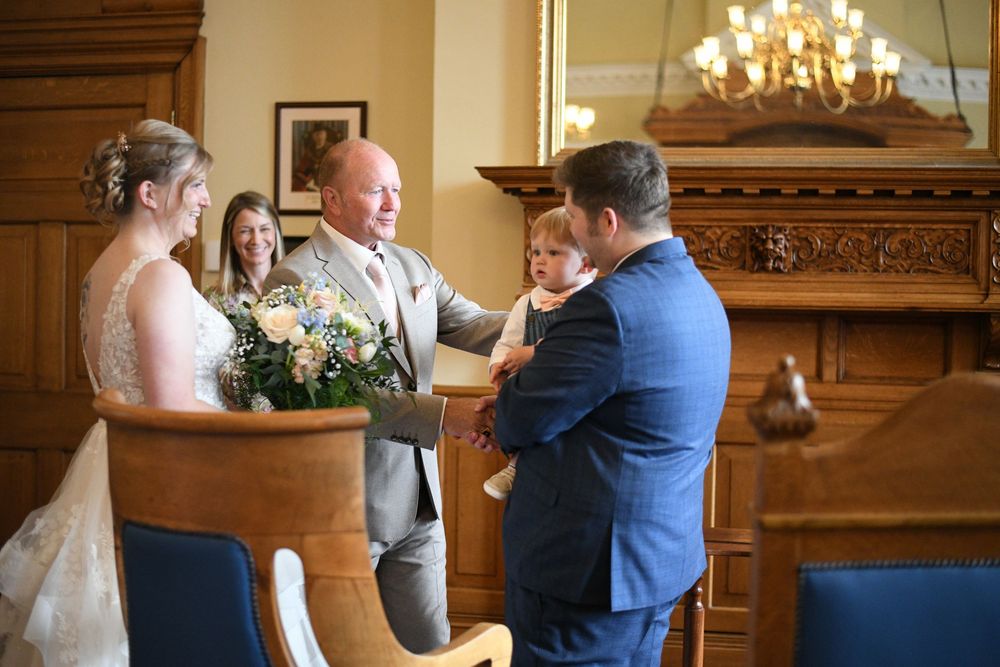 A sweet moment shared between loved ones during an indoor wedding ceremony with a chandelier and wooden decor.