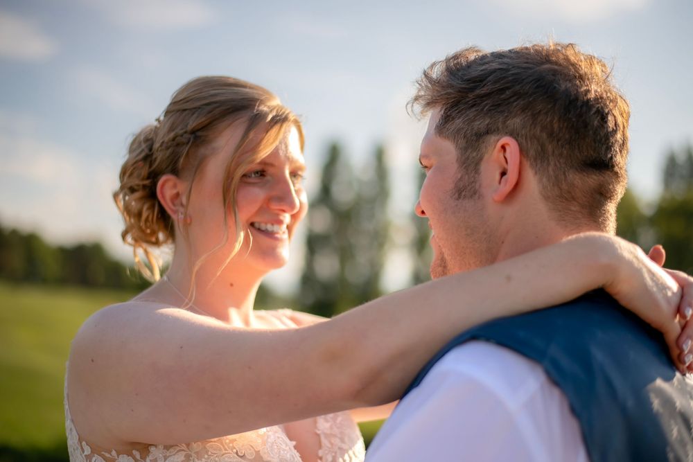 A happy outdoor moment shared between a couple at sunset, with warm lighting and natural greenery in the background.