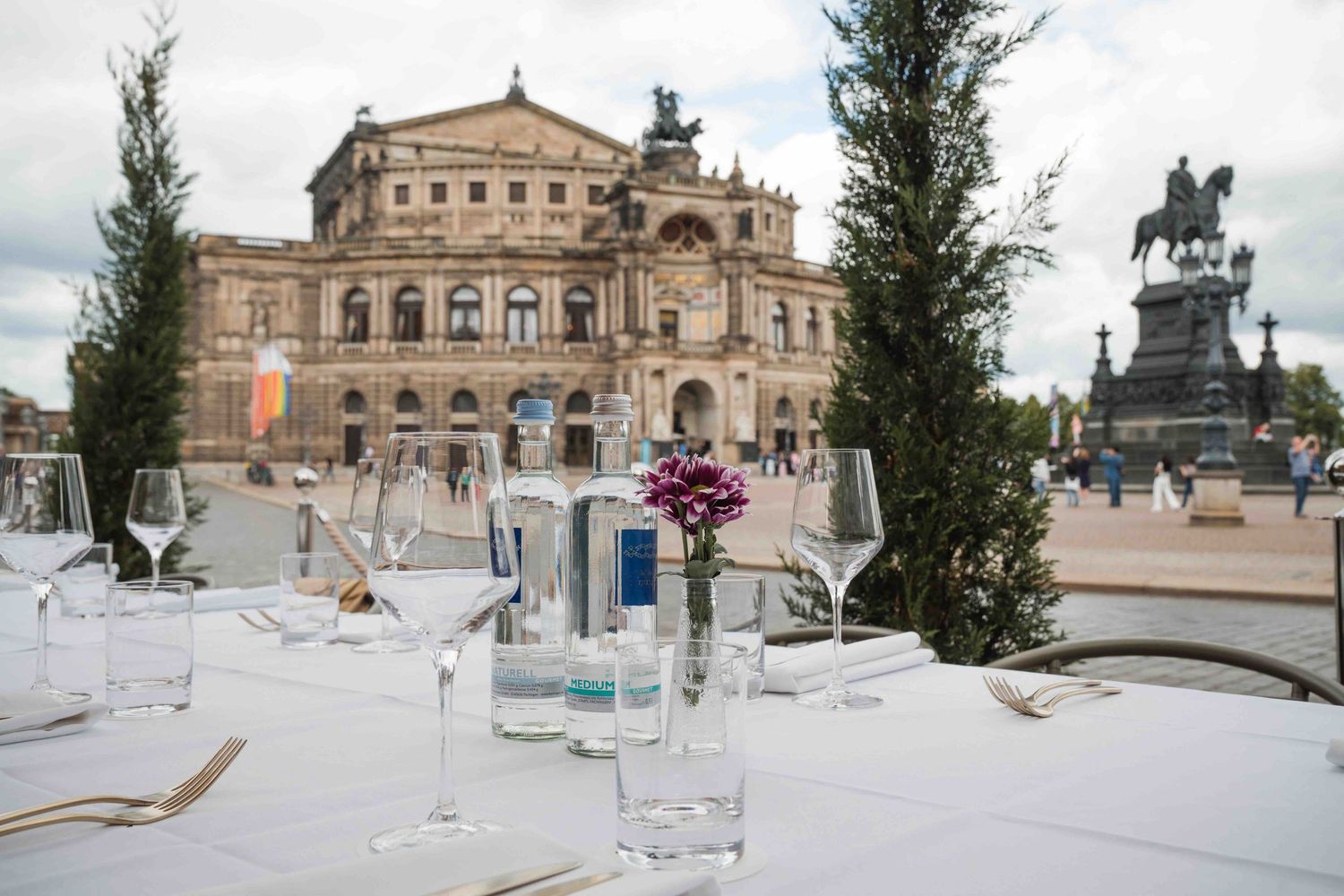 Elegant table setting with glasses in front of the historic Semperoper opera house in Dresden, Germany.