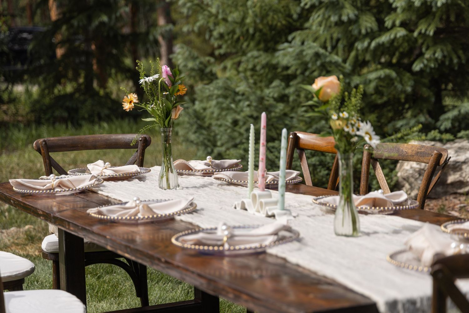 Rustic outdoor table settings with white linens and natural decor arranged for an elegant garden dining experience.