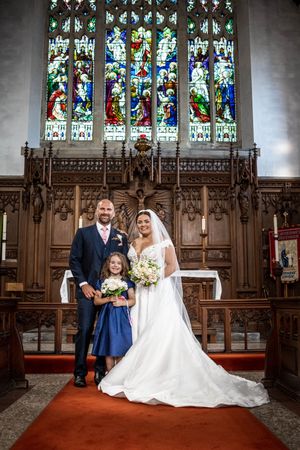 Wedding ceremony photos taken in a historic church with stained glass windows and ornate wooden details.