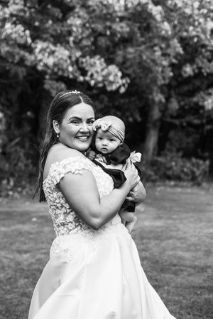 Black and white photos show heartwarming moments between a woman in a white dress and a baby in an outdoor setting.