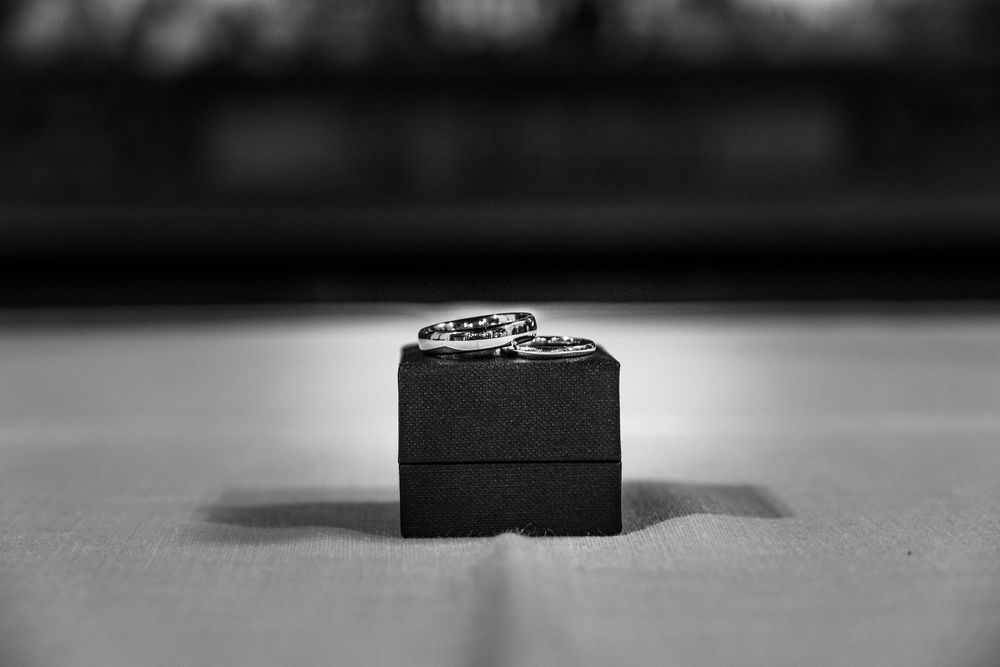 Close up black and white macro shot of a silver watch gear mechanism against a plain background.