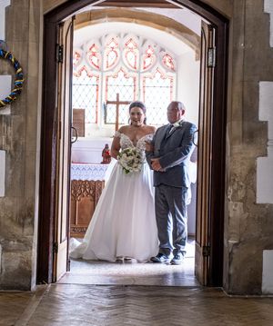 Cathedral wedding ceremony venue interior with stone columns and archways decorated with sunlight streaming through windows.