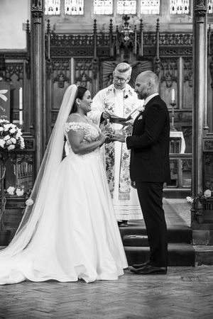 A wedding couple shares a tender dance moment in a grand room with ornate architectural details and flowing white gown.