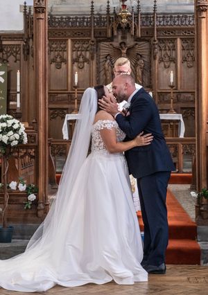 A sweet moment between newlyweds inside an ornate wooden church with beautiful Gothic architecture and decorative details.