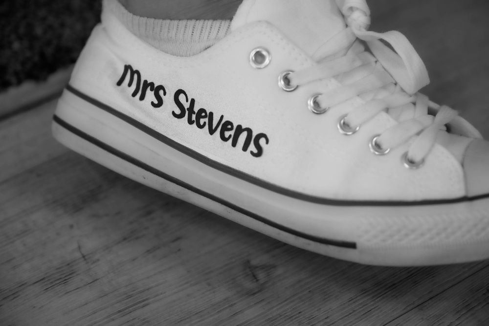 Custom white Converse sneakers with 'Mrs Stevens' text printed on them arranged in a sequence.