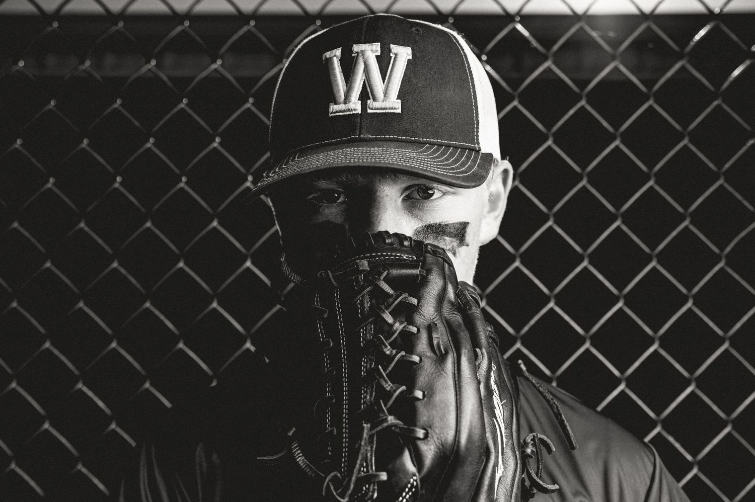 A black and white photo montage shows close-up portraits with various baseball caps and somber expressions.